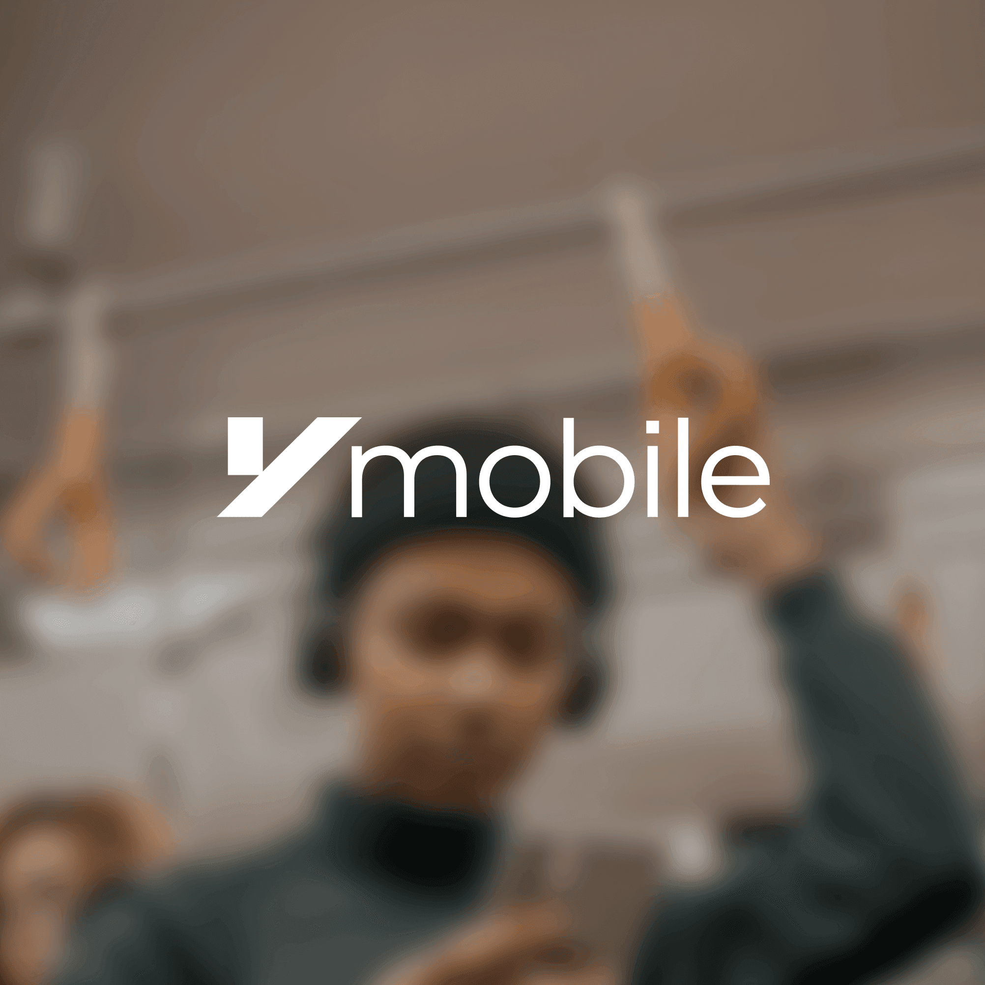 Image of Ymobile logo in front of a blurred background of someone on a phone riding on a train